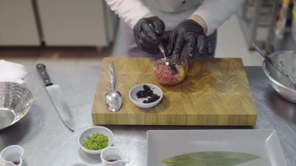 在现代餐厅厨房的特写镜头中 身穿黑色橡胶手套的厨师正在准备用金枪鱼和鲑鱼做的菜肴 男性在菜中加入调味料 味道鲜美的烹调概念 顶部视图 — 图库视频影像