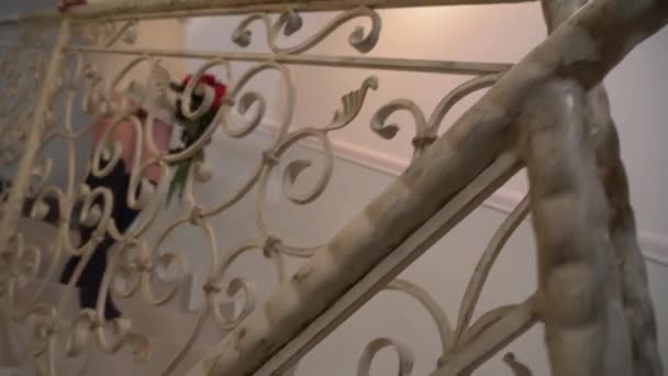 video ženy s kyticí růží, jak jde dolů po schodech. Mladá žena v krátké zimní svetr a punčochy je uvnitř velkého domu
