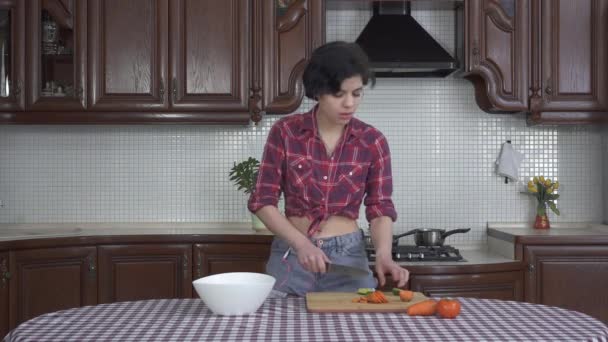 非常有趣的小女孩 戴着耳机 在木板上切蔬菜 在厨房跳舞 — 图库视频影像