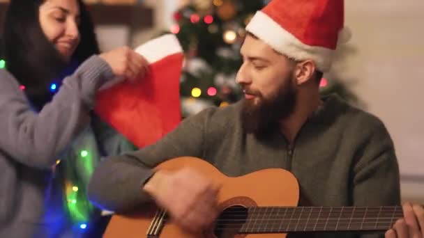 Man Playing Guitar Singing Sitting Floor Christmas Tree Woman Wearing — Stock Video