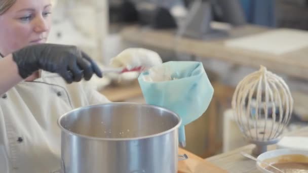 ケーキを飾るためにクリームのための特別な袋に調理されたバニラ混合物を置く制服の女性パン屋 — ストック動画
