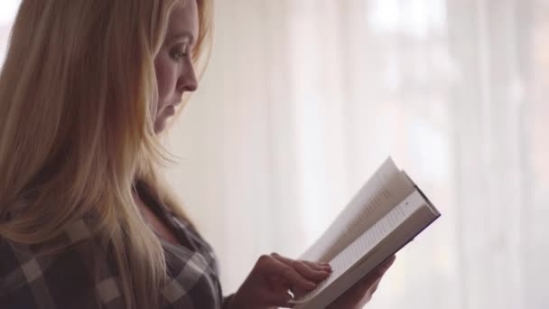 Vista Lateral Jovem Mulher Lendo Livro Interessante Sala Frente Grande — Vídeo de Stock