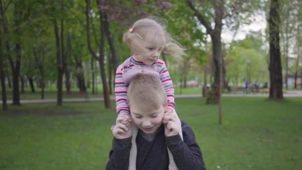 Yakışıklı Sarışın Çocuk Parkta Sevimli Kız Kardeşiyle Oynuyor Onu Omuzlarında — Stok video