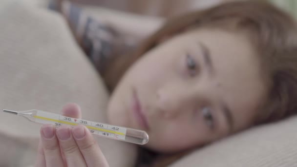 疲れて病気の女の子がベッドに横になり 温度計 ビデオ — ストック動画