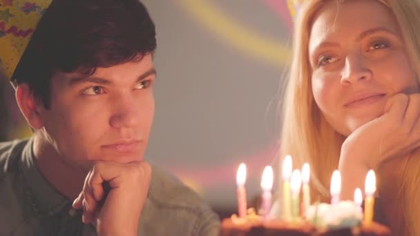 金发姑娘和一个头戴生日帽的男人坐在蛋糕前 手里拿着蜡烛 这个女人有一个生日庆祝活动 浪漫的家伙给女朋友准备了一个惊喜 — 图库视频影像