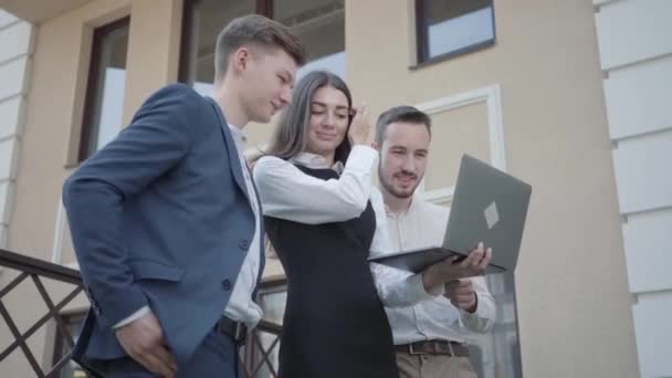 年轻女子和两名男子穿着正式服装 在阳台上的笔记本电脑上讨论这个项目 业务关系 自由职业的概念 遥远的工作 外面工作的人 — 图库视频影像