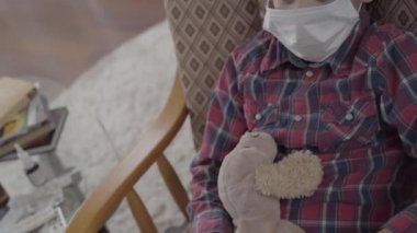 Küçük hasta çocuk koltuğunda oturmuş elinde tıbbi maskeyle oyuncak tutuyordu. 