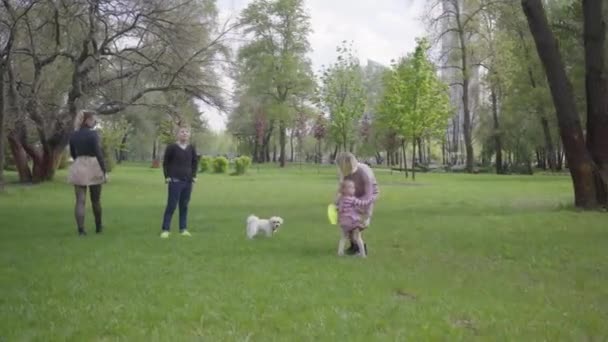 春の日に緑の素晴らしい公園で子供たちと遊んでいる2人の若い母親 ママと息子 娘が公園で遊んでいる 家族間の友情の概念 — ストック動画