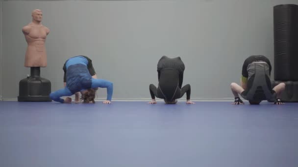 3人のチーム 男性と女性は ジムの床の上に頭を転がしている スポーツジムでのトレーニング — ストック動画
