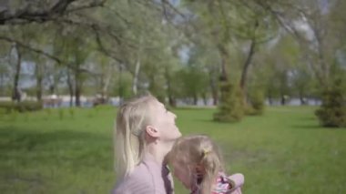 Genç pozitif anne küçük kızını kusar ve yakalar, ikisi de güler. Kaygısız çocukluğun kutlu olsun. Dışarıda dinleniyorum. Aktif sağlıklı yaşam tarzı, doğayla bağlantı