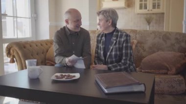 Masanın yanında oturan ve birbirleriyle konuşan mutlu çift.