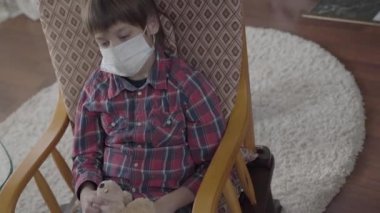 Küçük hasta çocuk koltuğunda oturmuş elinde tıbbi maskeyle oyuncak tutuyordu. 