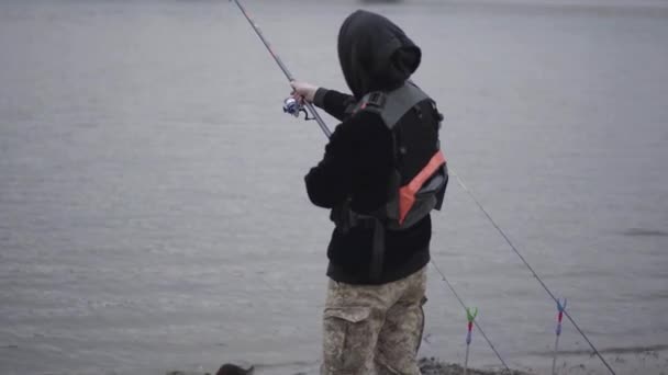 街の近くの川で釣りを回転早朝にカーキパンツで若い漁師を自信を持って — ストック動画