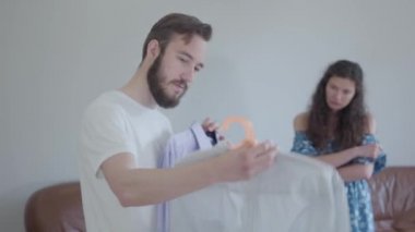 Video, yakışıklı sakallı adam eşine tavsiye gömlekleri soruyor, giysiler hazırlıyor. 