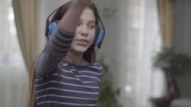 Kulaklıklı mutlu kız dans ediyor ve evde müzik dinliyor.