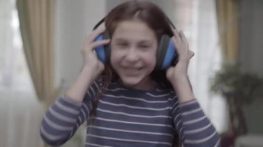Kulaklıklı mutlu kız dans ediyor ve evde müzik dinliyor.