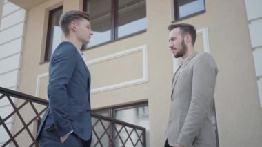 İki genç iş ortağı terasta el sıkışıyor. Adamlar harika bir anlaşma yaptı. İş ilişkisi. Alt görünüm videosu 