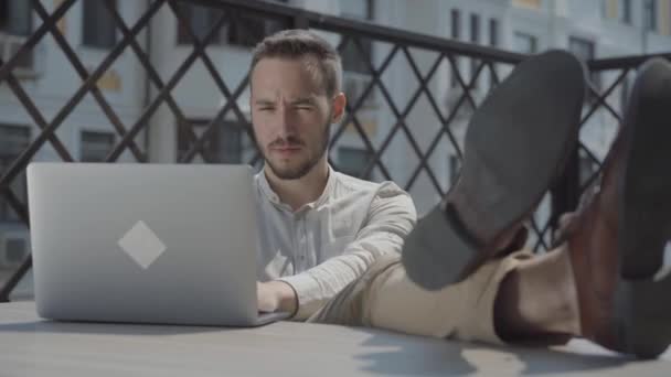 Бородатий Молодий Чоловік Сидить Столом Терасі Ногами Столі Ноутбук Лежить — стокове відео