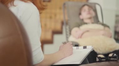 Psikoloğun ofisindeki bir karyolada oturan rahat genç adam ona yumuşak yastık tutarken yaşadığı sorunları anlatıyor. Genç bir hastaya kadın psikolog danışmanlık yapıyor. Kamera sağa hareket ediyor