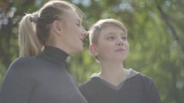 Genç bir anne ve genç oğlu parkta birlikte dinleniyorlar. Çocuğunu yanağından öpen kadın, çocuk da onu öpüyor. Mutlu dost bir aile. Boş zamanlarımız var.