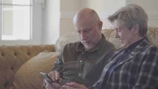 Senior Couple Sitting Big Sofa Bald Man Showing Photos Mobile — Stock Video