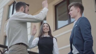 Genç bir kadın ve resmi olarak iki erkek terasta birlikte beşlik takıyor. İş ilişkisi, video 