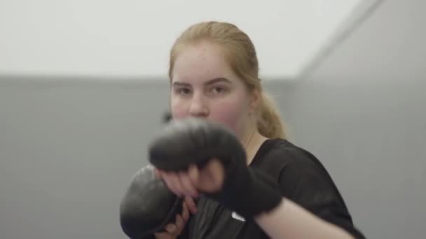 年轻的金发姑娘戴着拳击手套在镜头前喘息 — 图库视频影像