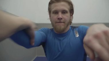 Komik sarışın sakallı adam başka bir adamla güreşiyor. Spor salonunda ellerini tutmaya çalışıyor. İki sporcu antrenmanda oynaşıyor. İlk ateş eden kişi.