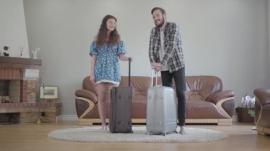 Mutlu çift portresi büyük bavullar ve gülümseme ile evde durur, video