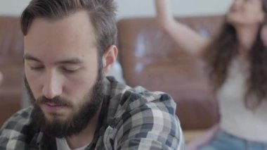Mutlu bir eş arka planda eşarp denerken sakallı bir adamın portresi. Tasasız kız ve ciddi adam, video.