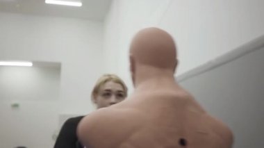 Genç, güzel sarışın bir kadın spor salonunda bir mankenle boks yapıyor. Dövüş. Antrenman. Dövüş sanatları.