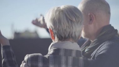 Gökyüzüne bakıp birbirleriyle iletişim kuran yaşlı bir çiftin arka görüntüsü. Dışarıda evli bir çift var..