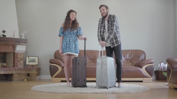 幸せなカップルの肖像画は大きなスーツケースと笑顔で家に立つ ビデオ — ストック動画