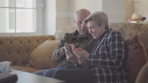 Oudere Echtpaar Zit Grote Bank Kale Man Toont Foto Mobiele — Stockvideo