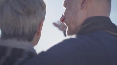 Gri kısa saçlı, açık havada duran kel bir adamın sırtında..