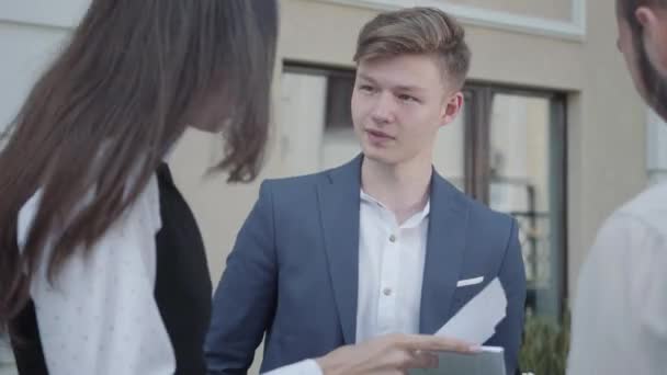 Drie Jonge Medewerkers Discussiëren Een Project Terwijl Papieren Documenten Buiten — Stockvideo