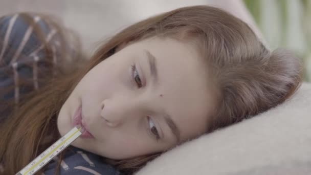 悲しい疲れ病気の女の子寝そべっているベッドで温度計で口 ビデオ — ストック動画