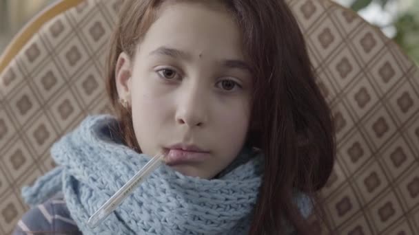 彼女の口の中に温度計を保持している暖かいスカーフに包まれた10代の女の子の肖像ビデオ — ストック動画