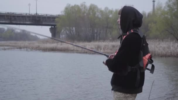 Впевнений Молодий Рибалка Штанях Хакі Вранці Обертається Риболовля Річці Поблизу — стокове відео