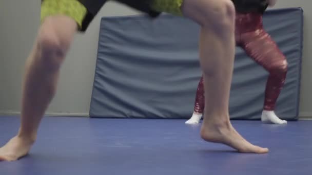 在体育馆里训练的男男女女的脚靠得很近 打斗前热身 男人和女人的腿都在脚趾上转动 那个男人光着脚 那位女士穿着袜子 — 图库视频影像