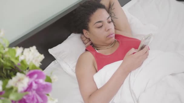 Видео Молодая Афроамериканка Лежит Постели Пишет Смс Мобильный Телефон — стоковое видео