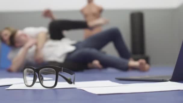 两个身穿白衬衫的男人躺在地板上摔跤的模糊形象 前台地板上的纸 笔记本电脑和眼镜 竞争概念 — 图库视频影像