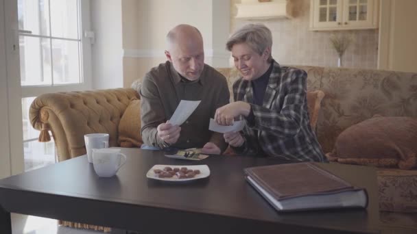 Adult Couple Sitting Couch Examines Old Photos Shares Memories — ストック動画