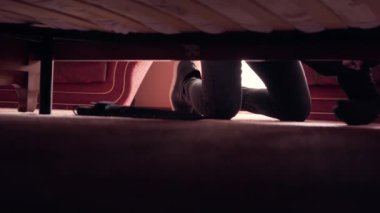 Siyah elbiseli ve kar maskeli hırsız para için yatağın altına bakıyor. Bir şeyler çalan adam. Suç kavramı, suçlu, kanunlara karşı suç. Yatağın altından ateş ediyor.