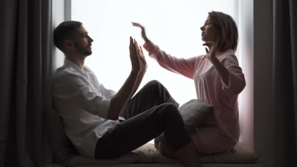这对可爱的夫妇一起坐在窗台上玩着 拍拍蛋糕 的游戏 丈夫和妻子在家里休息 在室内休息 男人和女人在一起玩 友好关系概念 — 图库视频影像