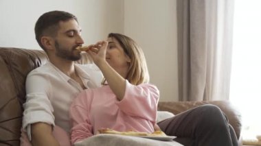 Kocasına nefis ev yapımı pizza yedirip deri koltukta oturan sıradan elbiseli kadın portresi. Mutlu evli çift evde romantik bir akşam yemeği yer. İçerde zaman geçirmek. 