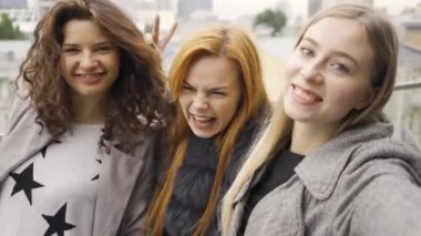 Üç güzel genç kız arkadaş bir kafedeki terasta selfie çekiyorlar.