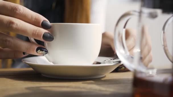 坐在咖啡厅里 一只黑指甲的高加索女人的特写手摸着白茶杯 年轻女人在室内放松 — 图库视频影像