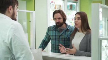 Genç beyaz bir çift internetten siparişlerini almak için eczaneye geliyor. Eczanede konforlu satın alma süreci. İnternet üzerinden ilaç alan mutlu müşteriler.