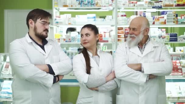 Tre kaukasiska apotekare tittar på varandra och på kameran. Mycket professionella anställda som stannar på sin arbetsplats. Människor i vita kläder som syftar till att rädda liv. — Stockvideo